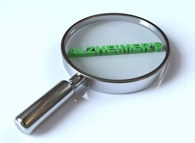 A magnifying glass focusing on the word "ALZHEIMER'S" in green text on a white background, emphasizing its importance in a medical context.