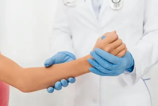 At the walk-in clinic, a person in a white coat and stethoscope checks another person's wrist while wearing blue gloves.