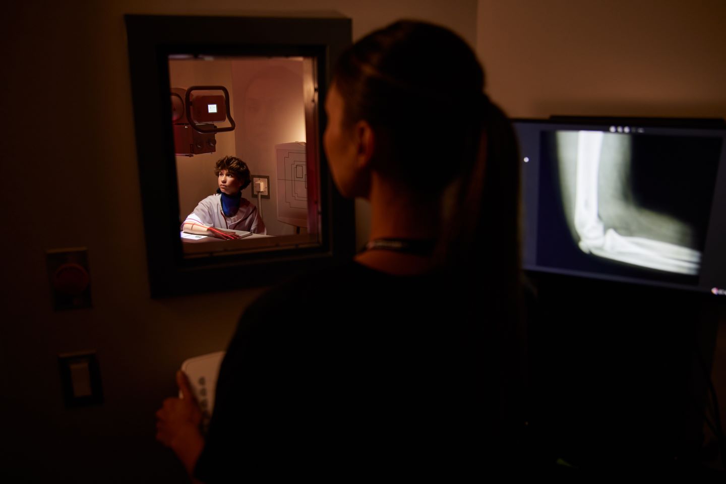 A person analyzing an X-ray image on a computer monitor, with another individual observing
