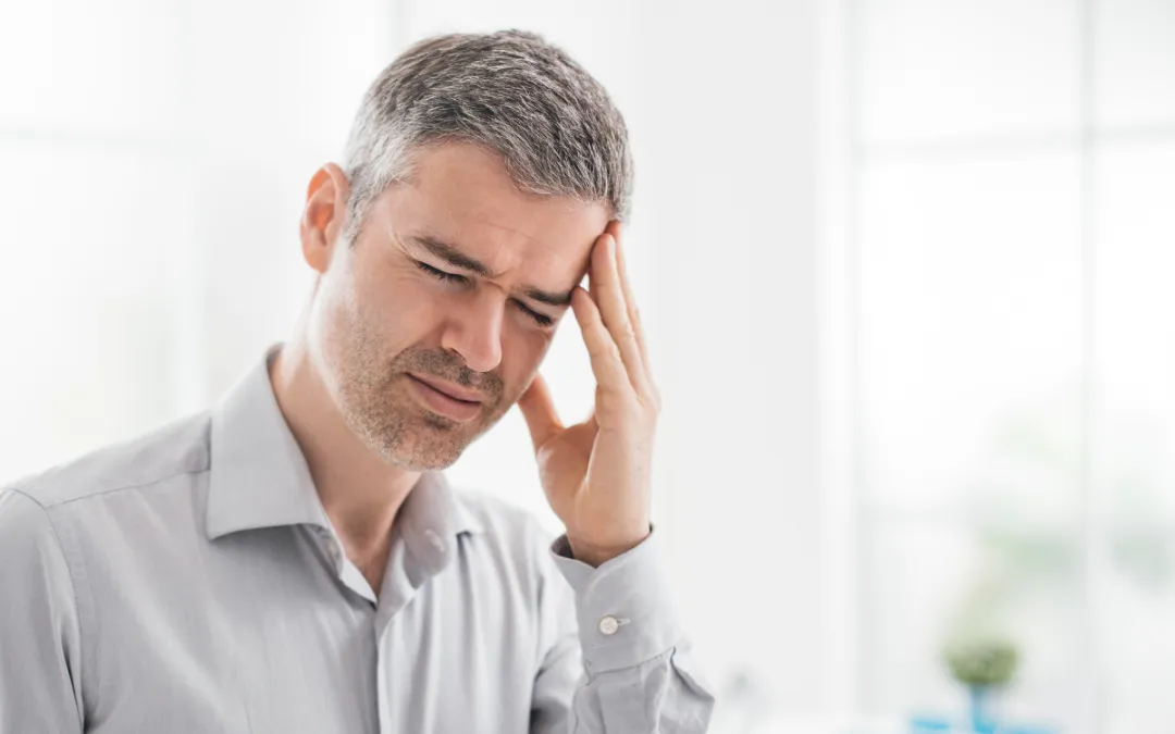 A sick man holds his aching head