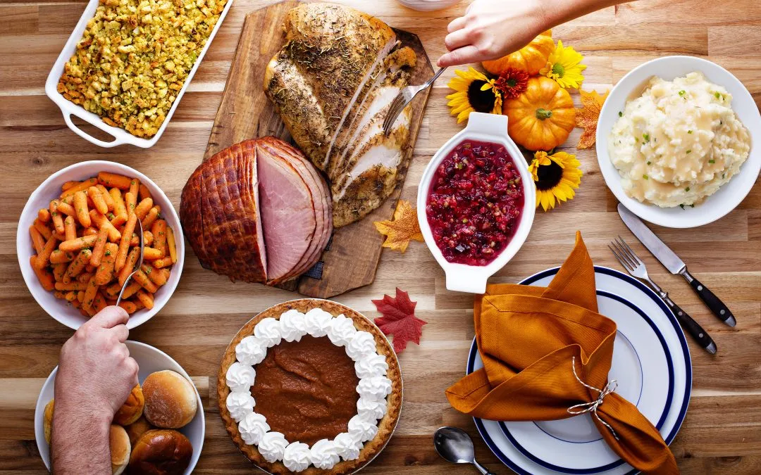 Hands reaching to serve themselves from a table of holiday food