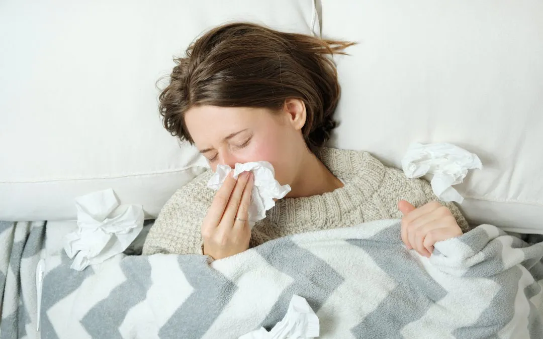 Sick woman covered in tissues in bed