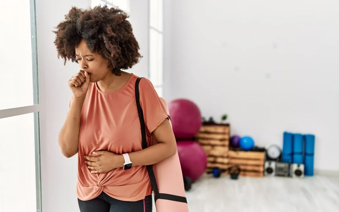 Woman at yoga coughs into her hand