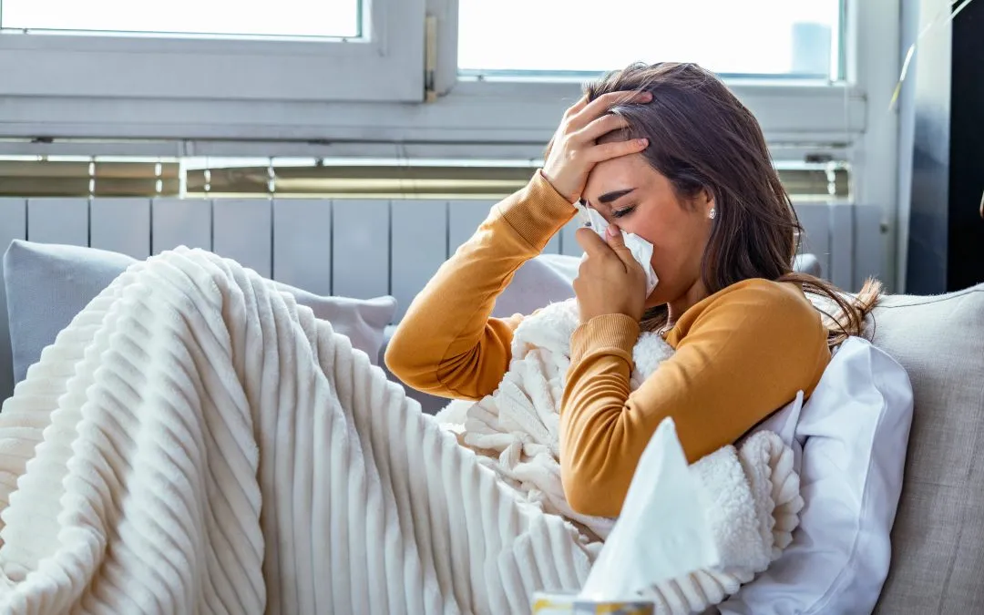 Woman in yellow shirt on the couch blows her nose